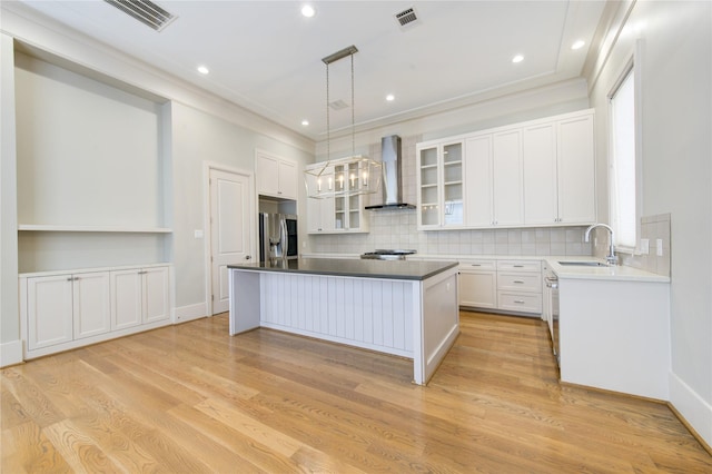 1509 Caywood Ln Unit C, Houston, TX 77055 - kitchen featuring wall chimney range hood, a sink, appliances with stainless steel finishes, a center island, and white cabinetry