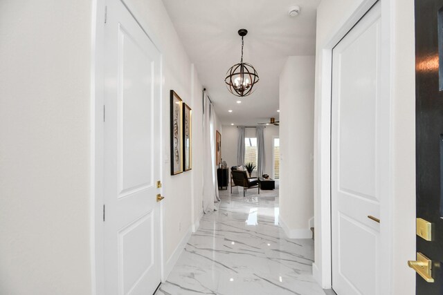 corridor featuring a chandelier, marble finish floor, baseboards, and recessed lighting