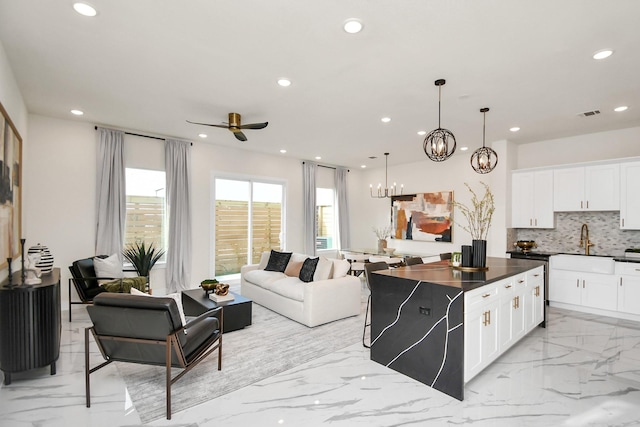 kitchen with recessed lighting, marble finish floor, tasteful backsplash, open floor plan, and ceiling fan with notable chandelier