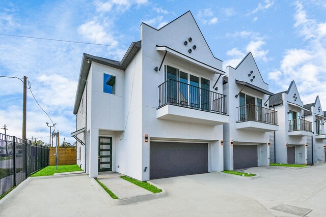 view of front of home with stucco siding, fence, driveway, and a garage