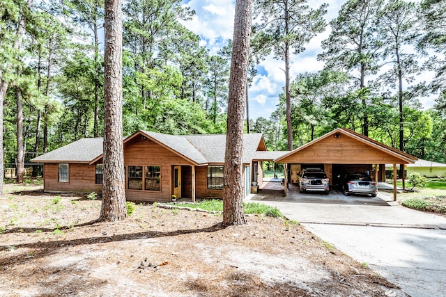 view of front facade featuring driveway, roof with shingles, and a carport