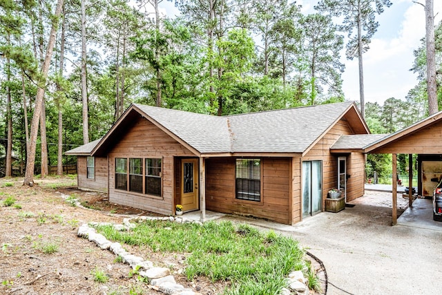 rustic home with a carport, roof with shingles, and concrete driveway
