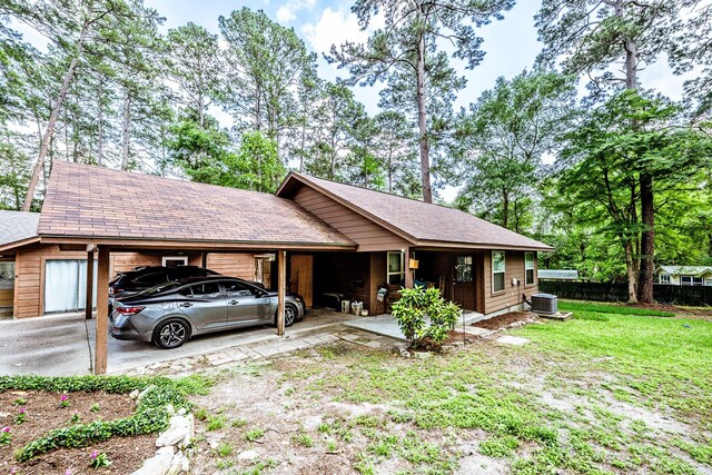 view of front of house with driveway, a front yard, central AC unit, fence, and an attached carport