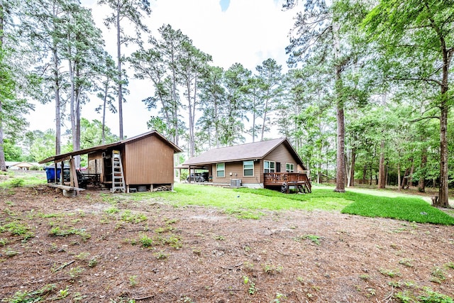 back of property with an outdoor structure, a yard, a deck, and cooling unit