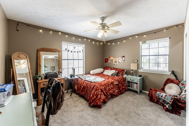 bedroom featuring a ceiling fan, a textured ceiling, and light carpet