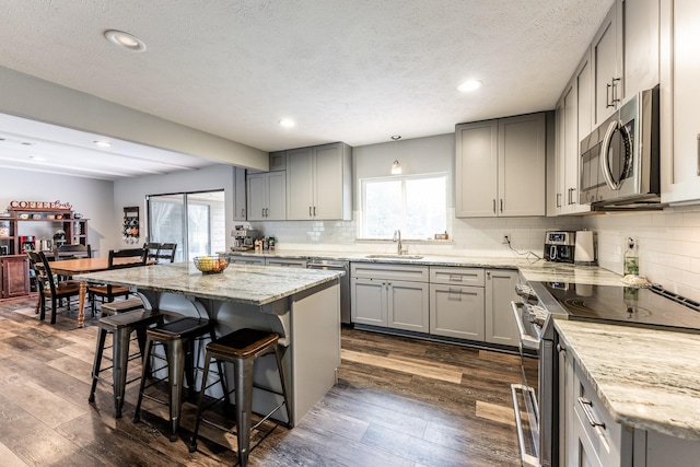 kitchen with a sink, appliances with stainless steel finishes, dark wood-style floors, and gray cabinets