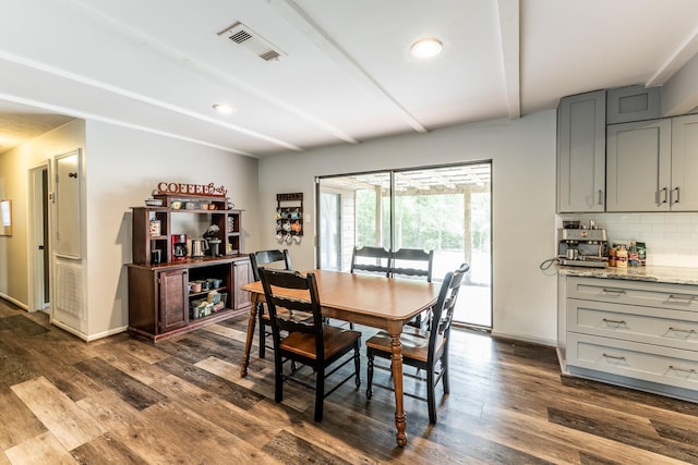 dining area with visible vents, dark wood finished floors, baseboards, and beam ceiling