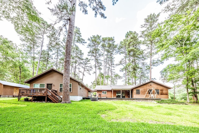 rear view of house featuring a lawn, a wooden deck, and stairs