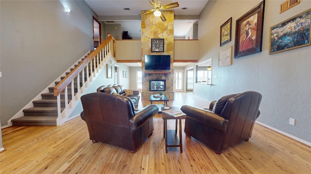 12708 Pelican Blvd, Willis, TX 77318 - living room with a stone fireplace, a ceiling fan, stairs, hardwood / wood-style floors, and a high ceiling