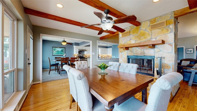 12708 Pelican Blvd, Willis, TX 77318 - dining area with beamed ceiling, light wood-style floors, ceiling fan, a fireplace, and baseboards
