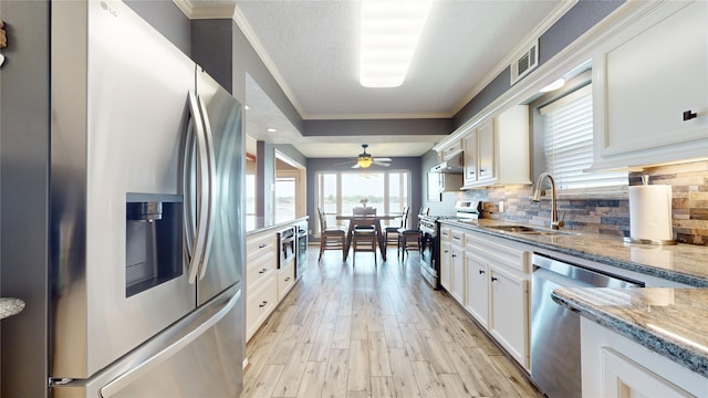 12708 Pelican Blvd, Willis, TX 77318 - kitchen with appliances with stainless steel finishes, a sink, light wood finished floors, white cabinetry, and backsplash