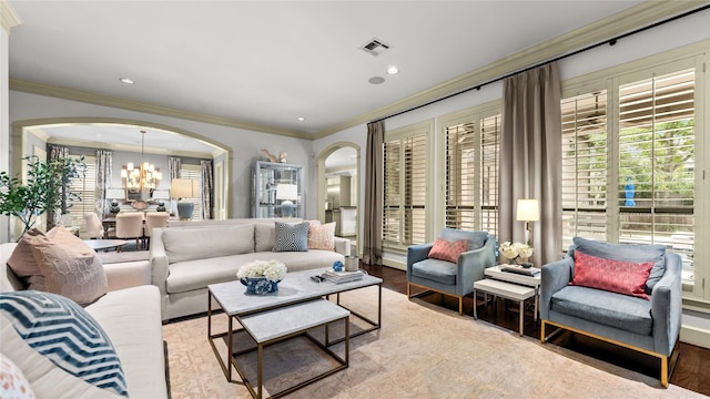 living area featuring crown molding, wood finished floors, arched walkways, an inviting chandelier, and visible vents