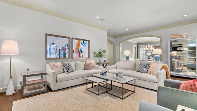 living room with wood finished floors, arched walkways, an inviting chandelier, ornamental molding, and recessed lighting