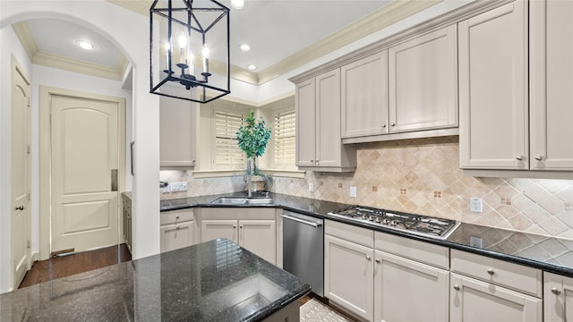 kitchen with a notable chandelier, dark stone countertops, appliances with stainless steel finishes, backsplash, and ornamental molding