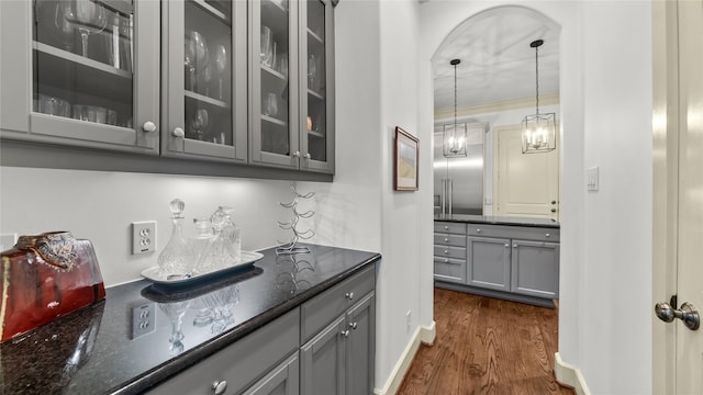 bar featuring a notable chandelier, arched walkways, decorative light fixtures, dark wood finished floors, and ornamental molding