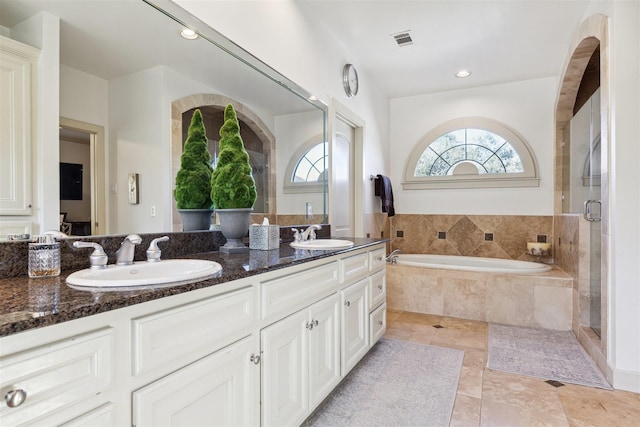 bathroom with a bath, visible vents, a sink, and double vanity