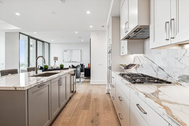 5656 San Felipe St Unit 603, Houston, TX 77056 - kitchen featuring stainless steel appliances, backsplash, a sink, light wood-style floors, and open floor plan