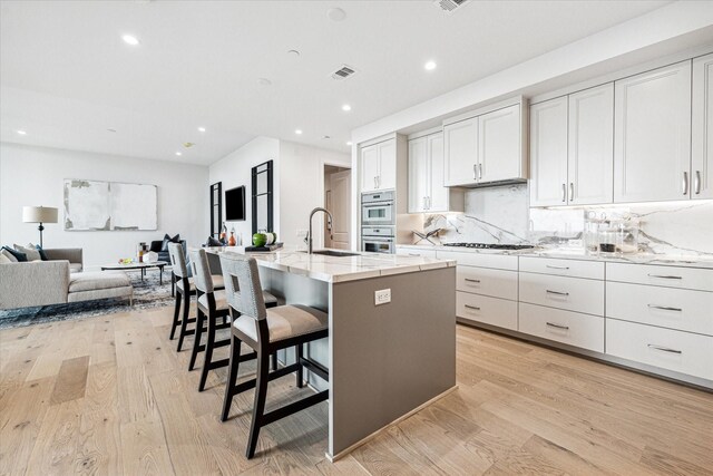 5656 San Felipe St Unit 603, Houston, TX 77056 - kitchen with recessed lighting, visible vents, a sink, light wood-style floors, and open floor plan