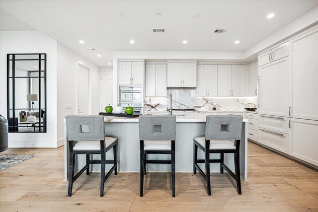 5656 San Felipe St Unit 603, Houston, TX 77056 - kitchen with light wood-style flooring, a kitchen island with sink, visible vents, and recessed lighting