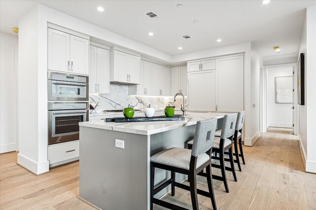 5656 San Felipe St Unit 603, Houston, TX 77056 - kitchen with light wood-type flooring, visible vents, light stone countertops, and double oven