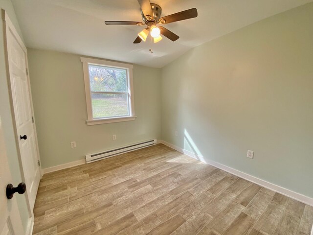 unfurnished bedroom featuring a baseboard heating unit, baseboards, and light wood-type flooring