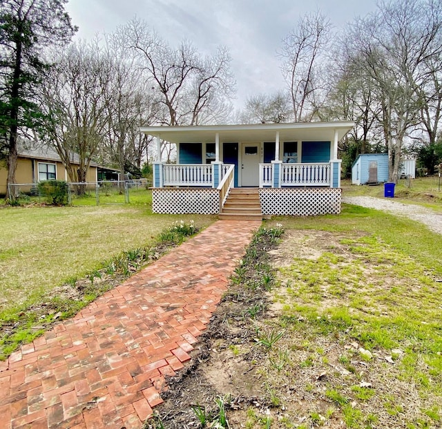 bungalow-style house with a porch, fence, an outdoor structure, a shed, and a front yard