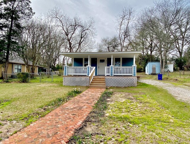 bungalow with fence, a storage shed, an outbuilding, covered porch, and a front yard