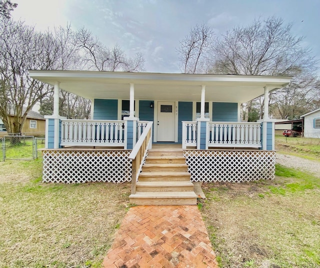 farmhouse-style home featuring fence, a front lawn, and covered porch