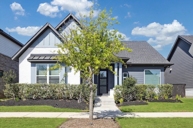 view of front of house featuring board and batten siding, a standing seam roof, a shingled roof, and a front yard