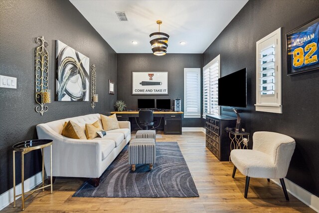 living area featuring baseboards, a textured wall, wood finished floors, and visible vents