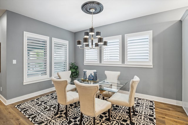 dining room with wood finished floors, baseboards, and an inviting chandelier
