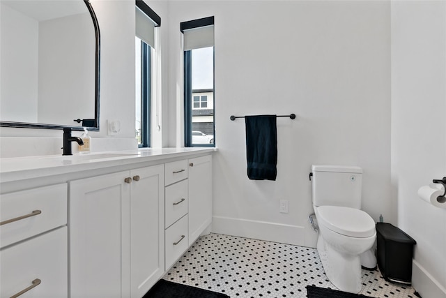 bathroom featuring baseboards, vanity, and toilet
