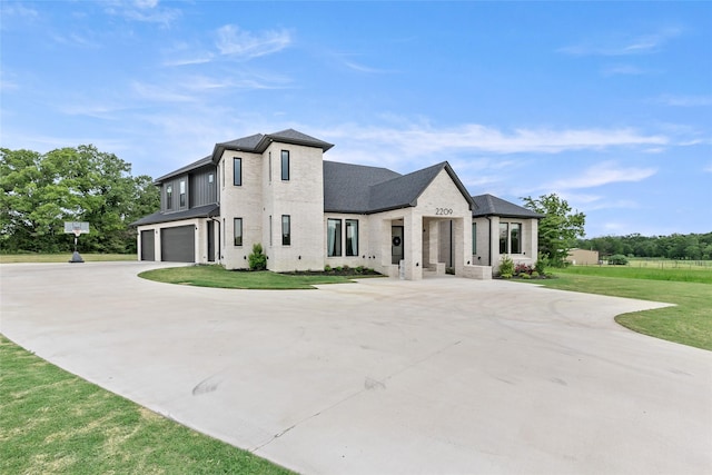 view of front of property with an attached garage, a front yard, brick siding, and curved driveway