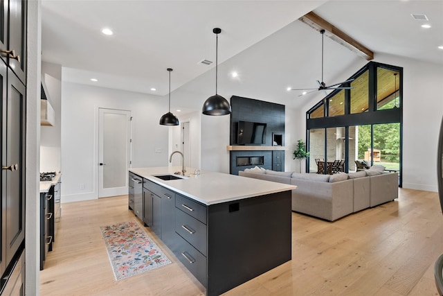 kitchen featuring light wood-style flooring, beam ceiling, a sink, ceiling fan, and light countertops