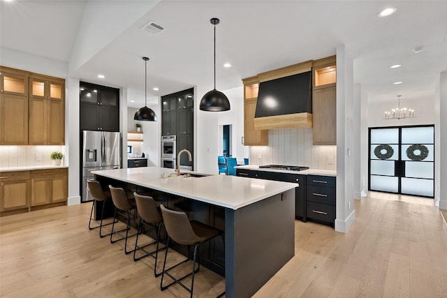 kitchen featuring backsplash, light wood-style floors, appliances with stainless steel finishes, and a large island