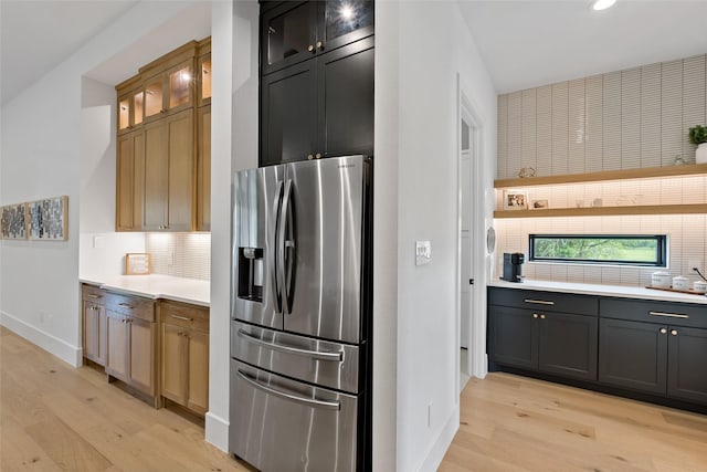 kitchen with decorative backsplash, stainless steel refrigerator with ice dispenser, baseboards, and light wood-style flooring