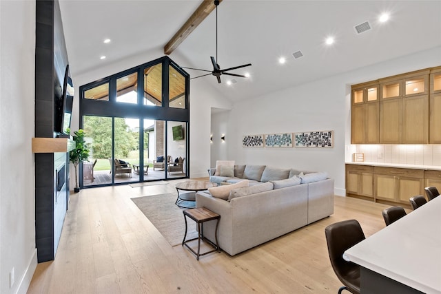 living room featuring light wood finished floors, visible vents, a ceiling fan, beam ceiling, and a large fireplace