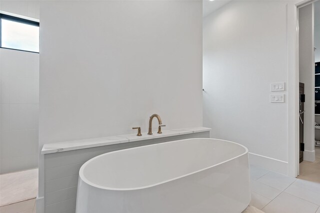 bathroom featuring a soaking tub, a spacious closet, and tile patterned floors