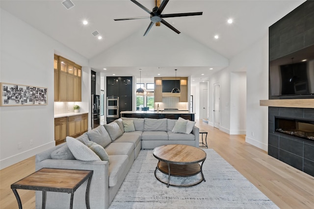 living room with light wood-style floors, visible vents, a ceiling fan, and baseboards
