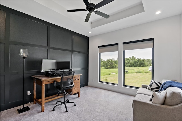 office space with a decorative wall, a ceiling fan, a tray ceiling, light colored carpet, and recessed lighting