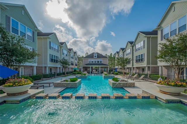 view of pool with fence, a pool with connected hot tub, a residential view, and a patio