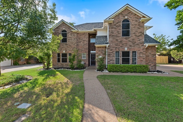 traditional home with brick siding, a shingled roof, a front yard, and fence