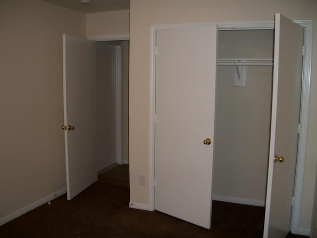 unfurnished bedroom featuring a closet and dark carpet