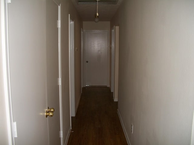 hall featuring baseboards, visible vents, and dark wood-type flooring