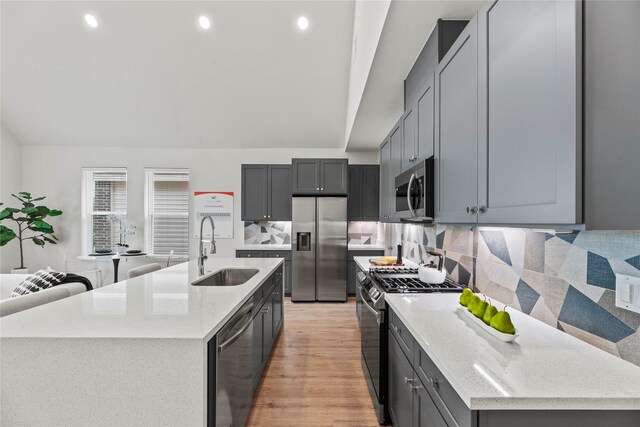 1046 Homer St, Houston, TX 77091 - kitchen with a sink, decorative backsplash, stainless steel appliances, a center island with sink, and lofted ceiling