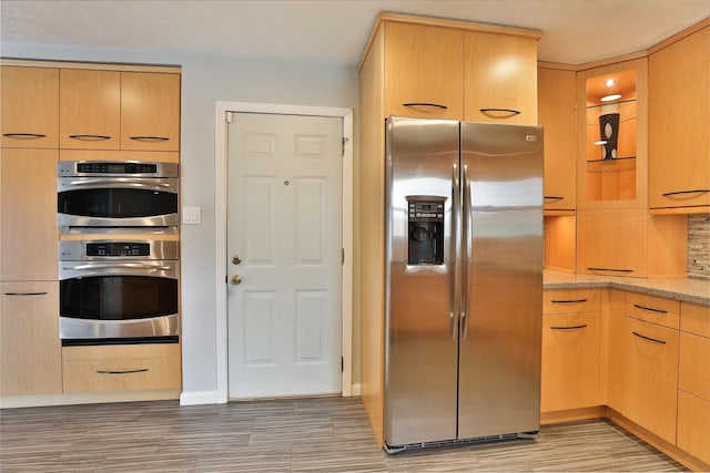 2427 Willowby Dr, Houston, TX 77008 - kitchen with stainless steel appliances, light wood-type flooring, glass insert cabinets, light stone counters, and light brown cabinets