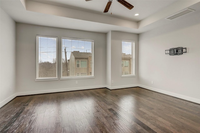 spare room featuring baseboards, visible vents, wood finished floors, ceiling fan, and a raised ceiling