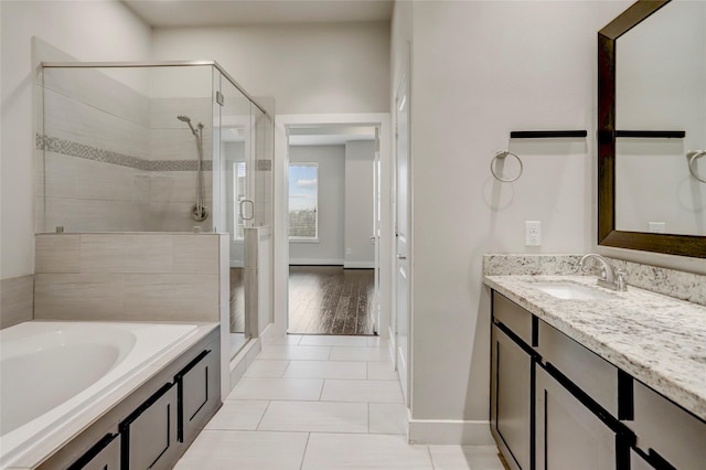 bathroom featuring a bath, a stall shower, baseboards, tile patterned flooring, and vanity