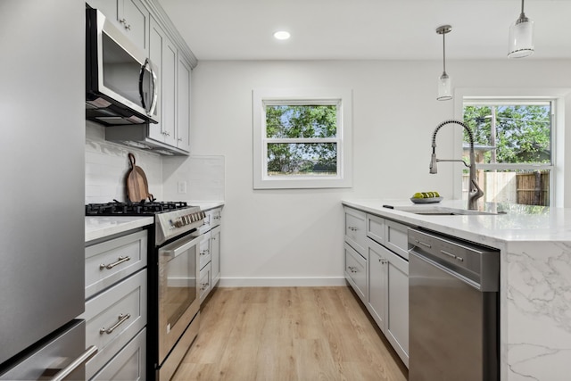 kitchen featuring decorative backsplash, stainless steel appliances, a sink, and plenty of natural light