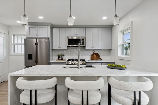 kitchen featuring gray cabinets, a healthy amount of sunlight, stainless steel appliances, and a sink